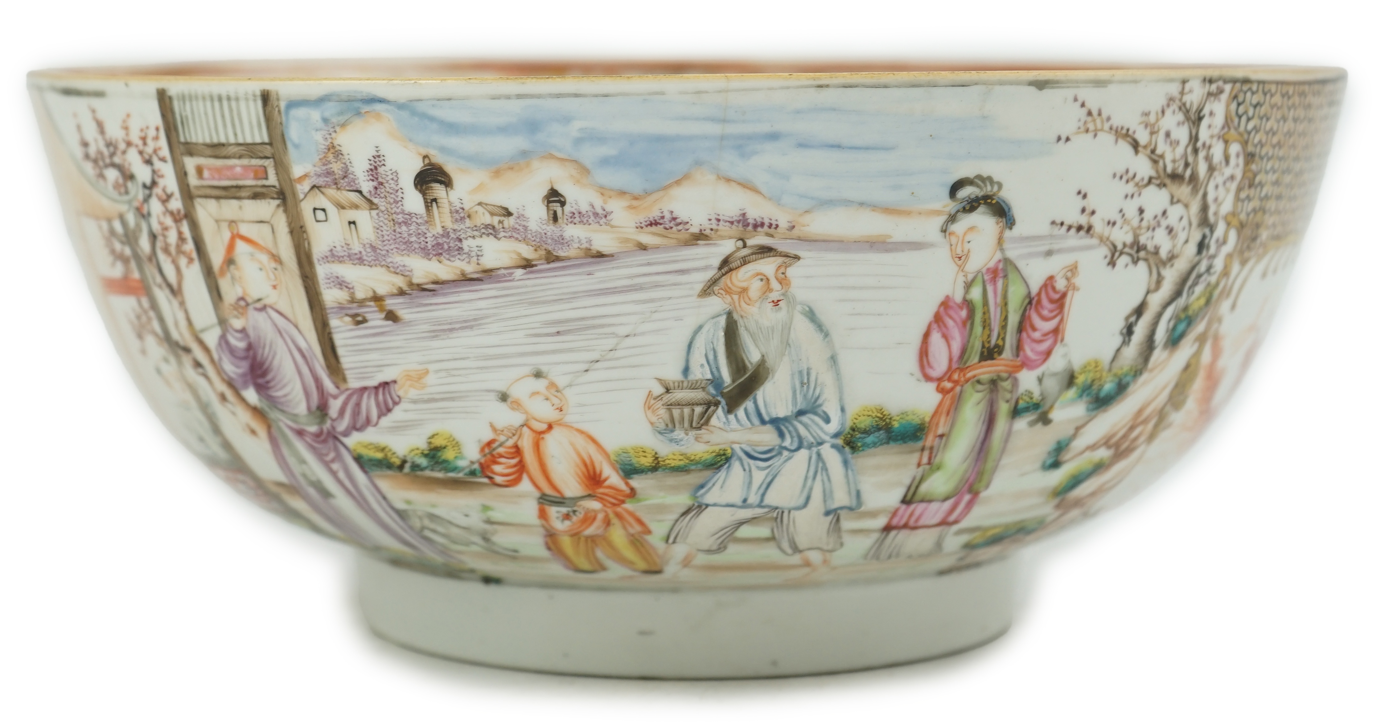 A Chinese famille rose ‘mandarin’ bowl, Qianlong period, painted with figures in a lakeside garden, between red enamelled landscape vignettes and cellular panels, 28.4cm diameter. Condition - there is a hairline crack to